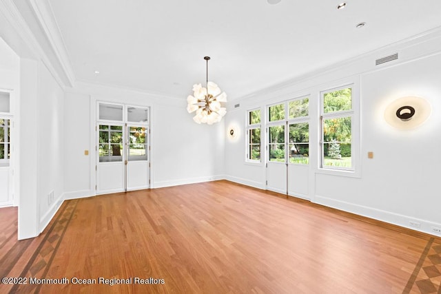 unfurnished dining area featuring crown molding, visible vents, a chandelier, and light wood-style floors