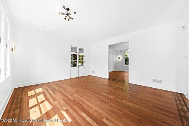 unfurnished living room with wood finished floors, visible vents, plenty of natural light, and a notable chandelier