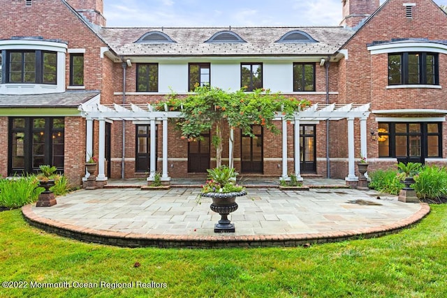 back of house with a high end roof, a patio area, and a pergola