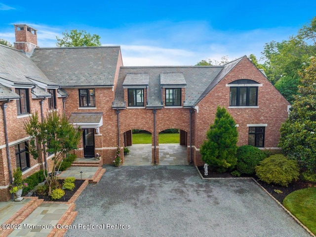 view of front of house featuring a high end roof, aphalt driveway, and brick siding