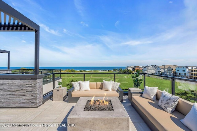 view of patio / terrace with an outdoor living space with a fire pit, a water view, and a balcony