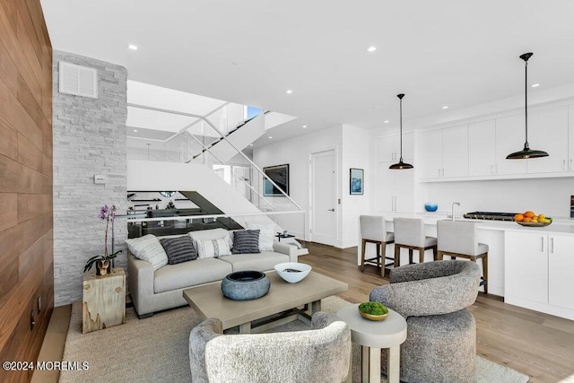 living room featuring wood finished floors, recessed lighting, and stairs