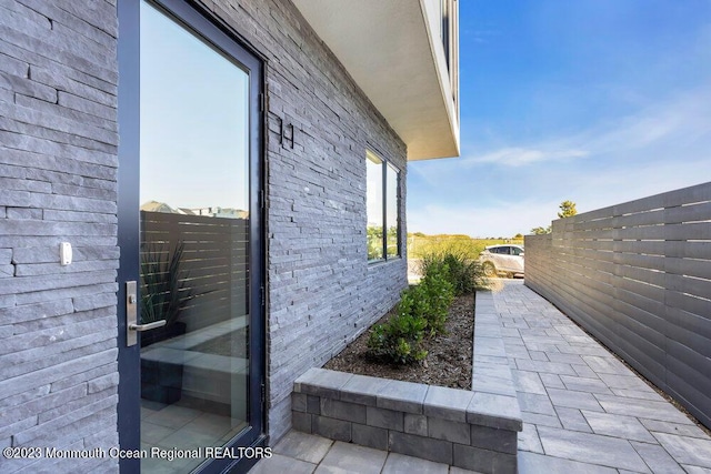 view of side of home featuring fence and brick siding