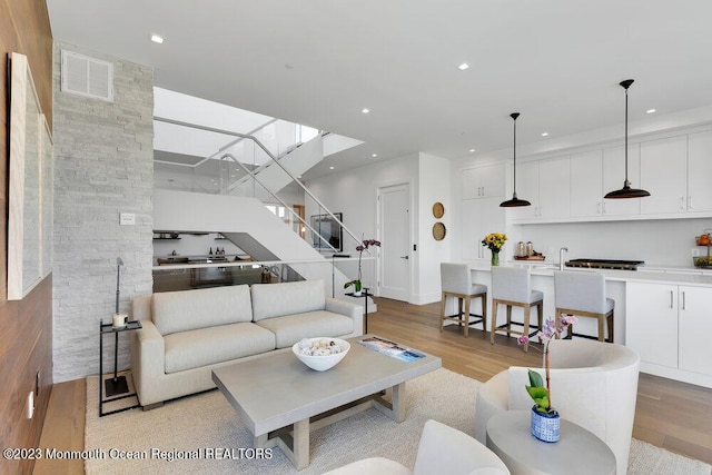 living room with visible vents, recessed lighting, light wood-style flooring, and stairs