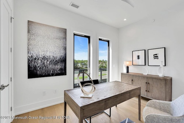 office with visible vents, a healthy amount of sunlight, light wood-style flooring, and baseboards