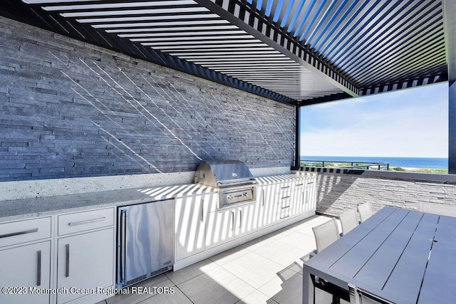 view of patio / terrace with grilling area, a water view, outdoor dining area, and an outdoor kitchen