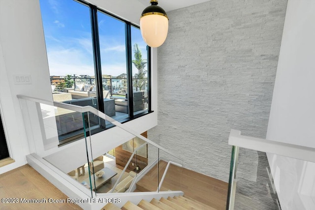 staircase with wood finished floors and a wall of windows