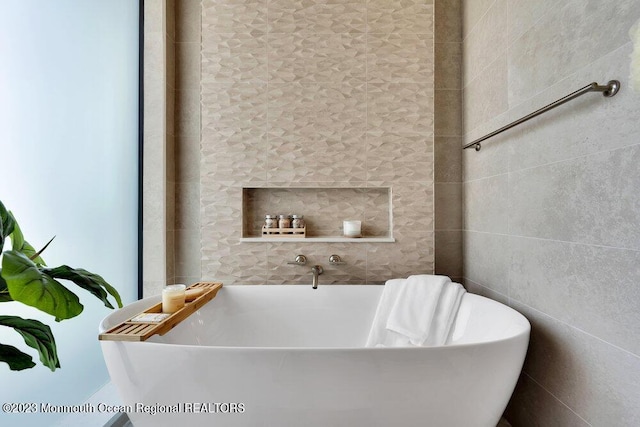 full bathroom with tile walls and a freestanding bath