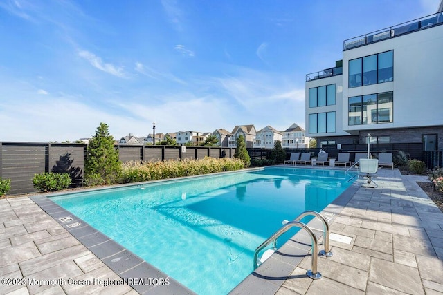 community pool featuring a patio area, a residential view, and a fenced backyard