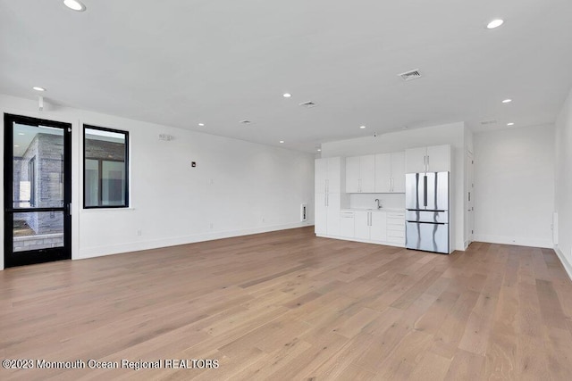 unfurnished living room featuring light wood finished floors, recessed lighting, visible vents, and baseboards