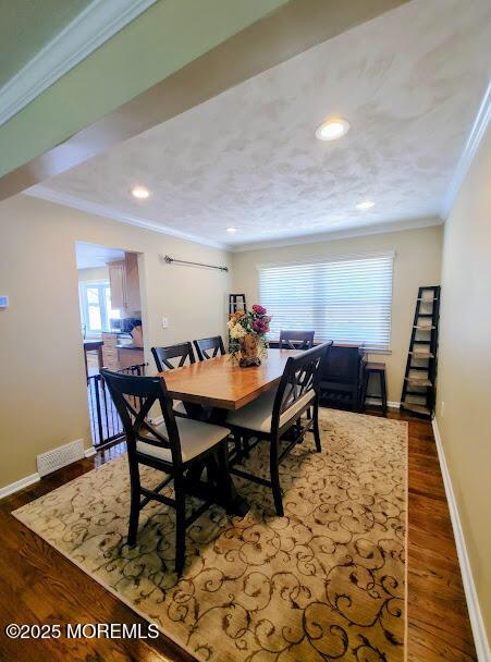 dining space featuring crown molding, baseboards, wood finished floors, and visible vents