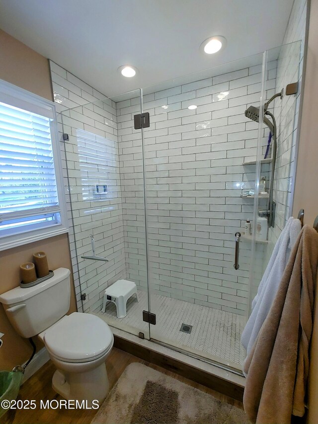 full bath featuring a shower stall, toilet, and wood finished floors