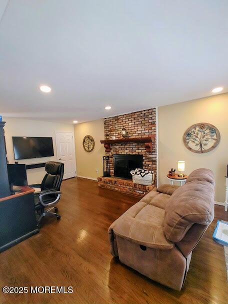 living room with recessed lighting, baseboards, a brick fireplace, and wood finished floors