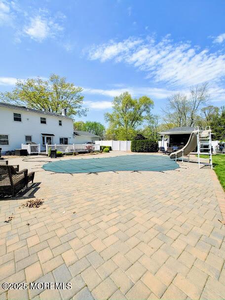 view of swimming pool featuring fence, a water slide, a patio, and a fenced in pool