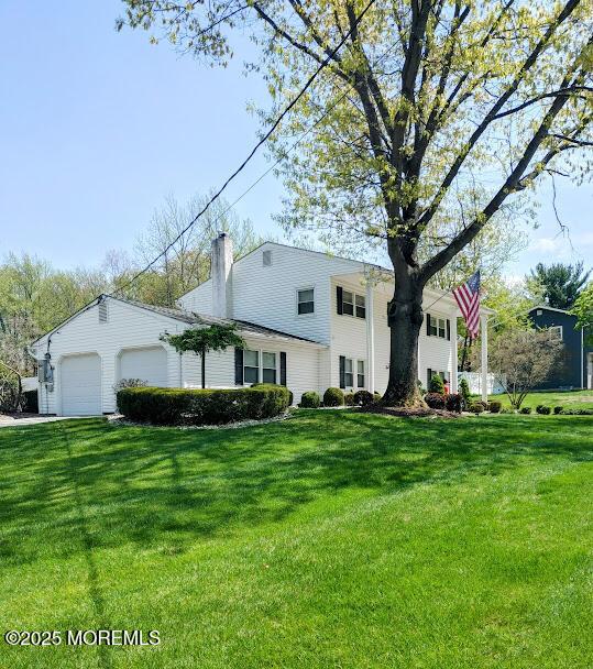 view of front of property with a chimney, a front lawn, and a garage
