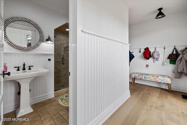 bathroom with a stall shower, a wainscoted wall, visible vents, a decorative wall, and wood finished floors