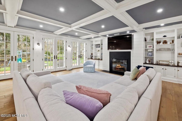 living room featuring coffered ceiling, light wood-style floors, a fireplace, beam ceiling, and french doors
