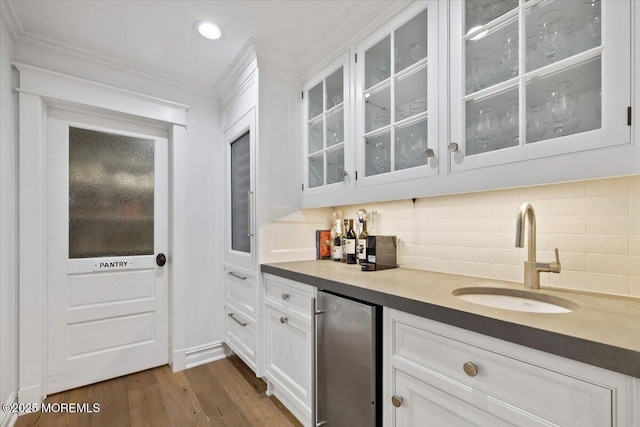 bar featuring dark wood-style floors, a sink, indoor bar, ornamental molding, and freestanding refrigerator