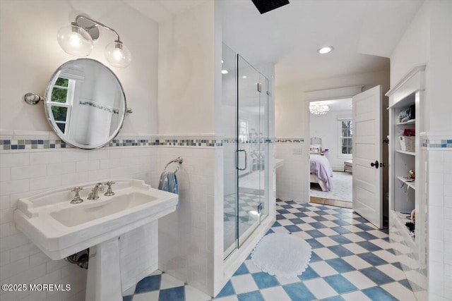 ensuite bathroom featuring a stall shower, tile walls, a wainscoted wall, and connected bathroom