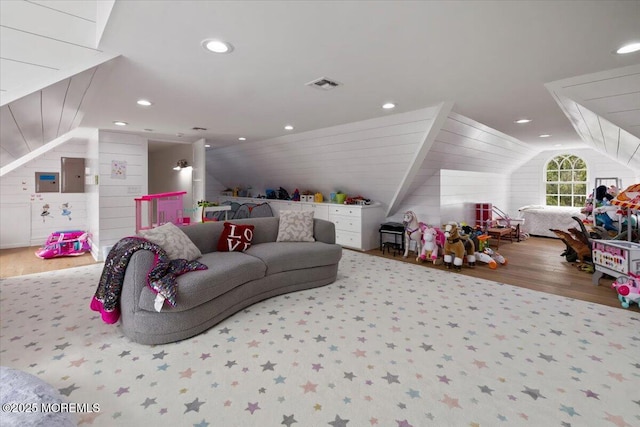 rec room with electric panel, wooden walls, visible vents, vaulted ceiling, and wood finished floors