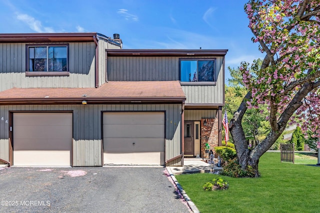multi unit property with a front lawn, roof with shingles, and driveway