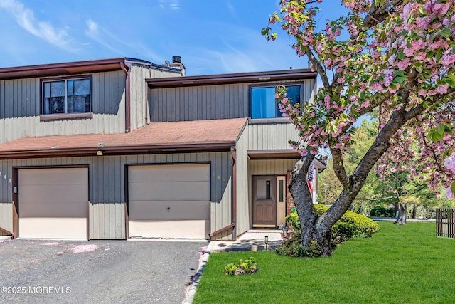 view of property featuring a garage, a front yard, and aphalt driveway