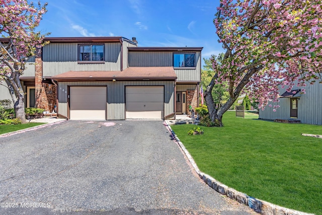 view of front of house with an attached garage, a front yard, and aphalt driveway