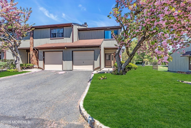 view of front of home with a garage, a front lawn, aphalt driveway, and a chimney