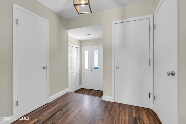 foyer featuring baseboards, wood-type flooring, and visible vents