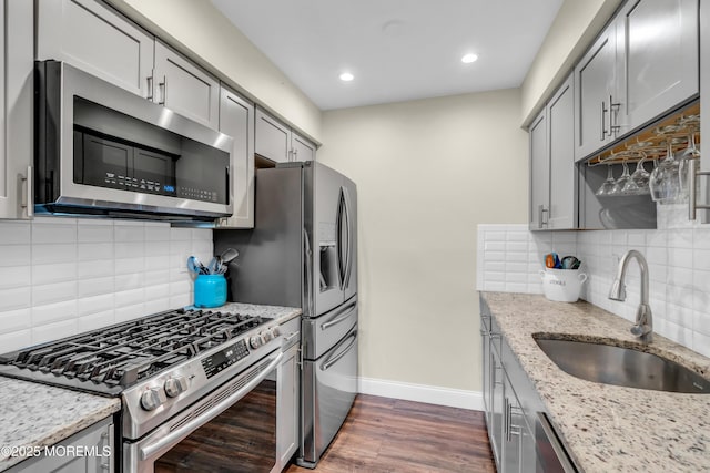 kitchen featuring a sink, baseboards, gray cabinetry, and stainless steel appliances