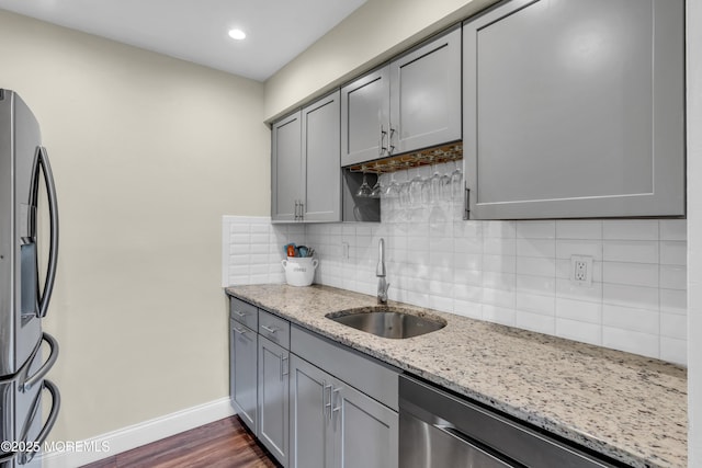kitchen featuring a sink, baseboards, gray cabinets, and stainless steel appliances