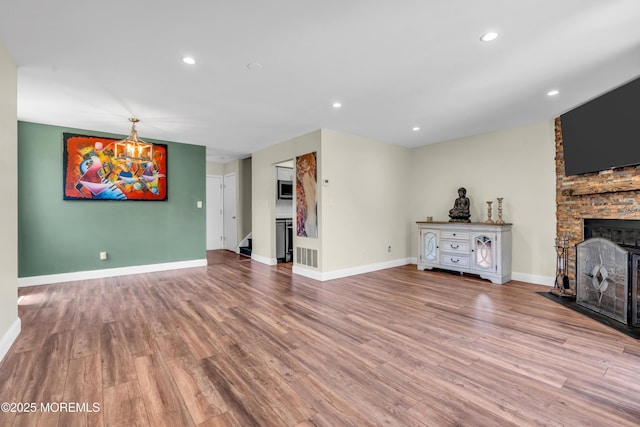 unfurnished living room with a fireplace, stairs, recessed lighting, baseboards, and wood finished floors