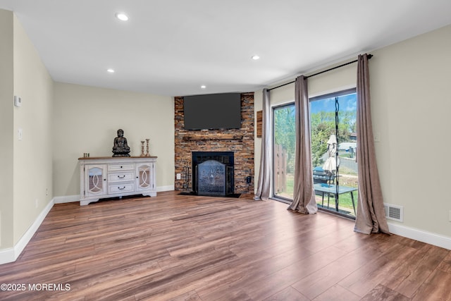unfurnished living room with a large fireplace, recessed lighting, baseboards, wood finished floors, and visible vents