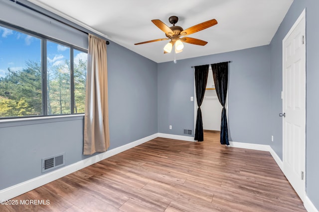 unfurnished room featuring baseboards, a ceiling fan, wood finished floors, and visible vents
