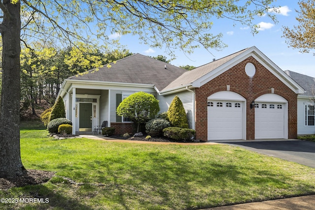 view of front of home with brick siding, a front yard, an attached garage, and aphalt driveway