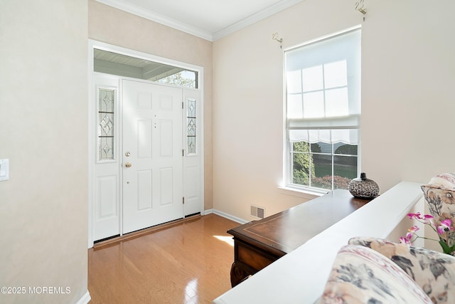entryway featuring wood finished floors, visible vents, crown molding, and baseboards
