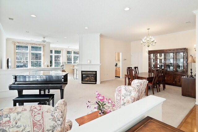 carpeted living area with recessed lighting, a large fireplace, visible vents, ornamental molding, and ceiling fan with notable chandelier