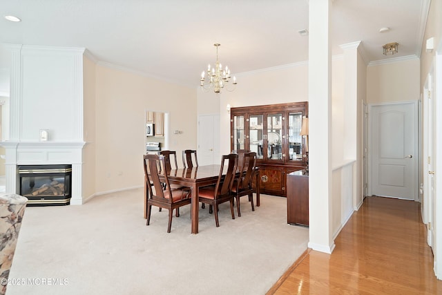 dining area with crown molding, baseboards, an inviting chandelier, light carpet, and a fireplace