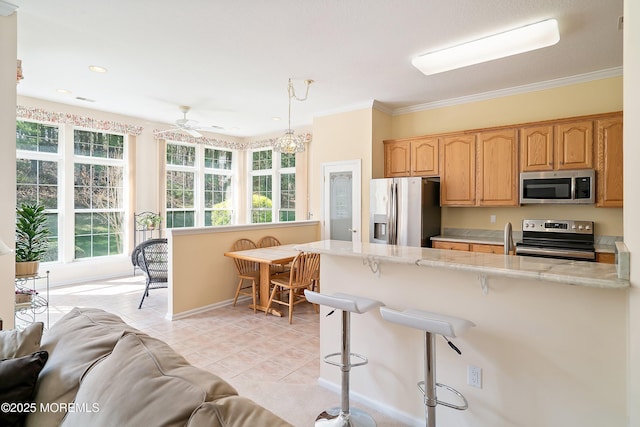 kitchen featuring appliances with stainless steel finishes, a peninsula, plenty of natural light, and a kitchen breakfast bar