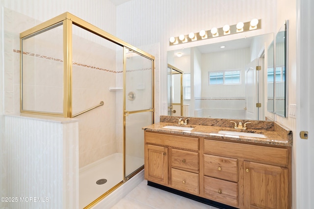 bathroom with a stall shower, wallpapered walls, and a sink