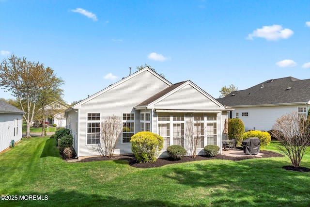 rear view of house featuring a lawn, a sunroom, and a patio area