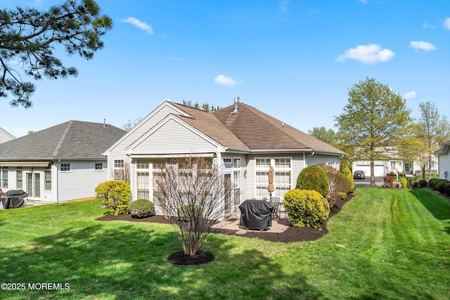 rear view of house featuring roof with shingles, a yard, and a patio area