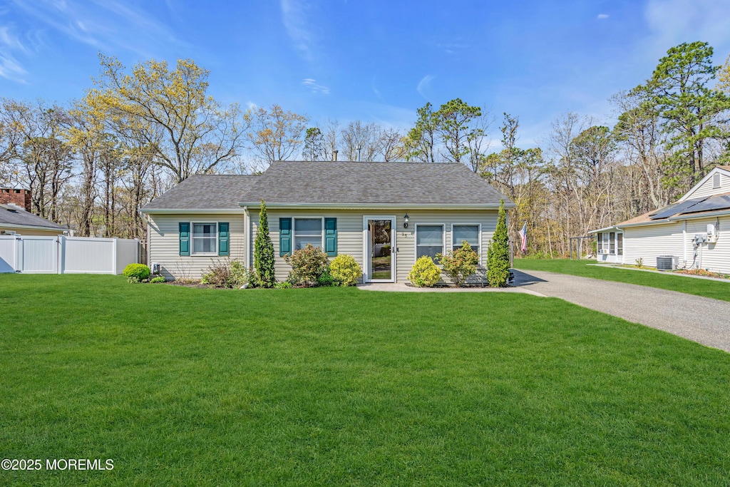 view of front of property with fence, central air condition unit, a shingled roof, and a front lawn