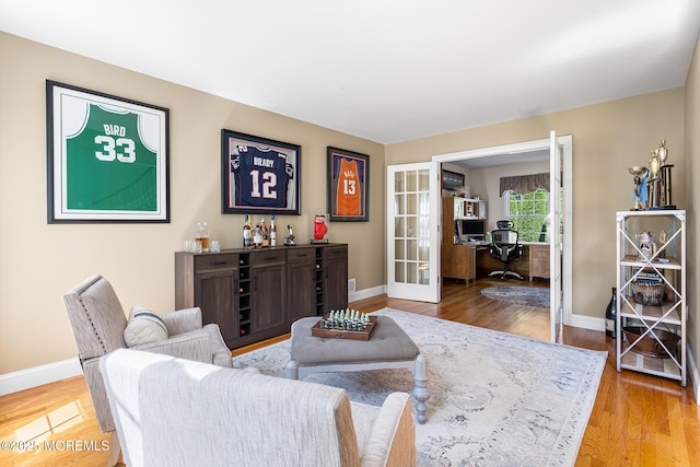 living area featuring french doors, baseboards, and wood finished floors