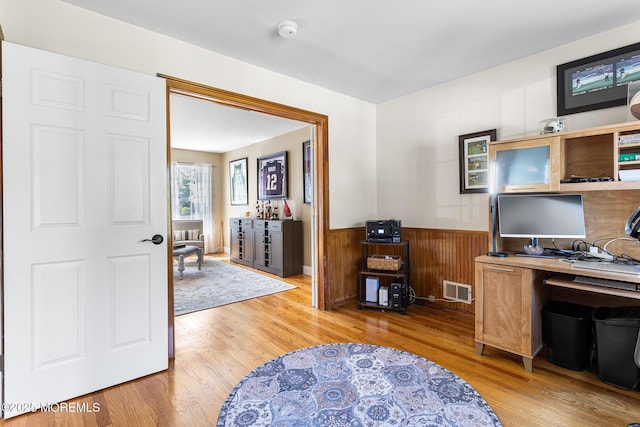 office with a wainscoted wall, wood walls, wood finished floors, and visible vents