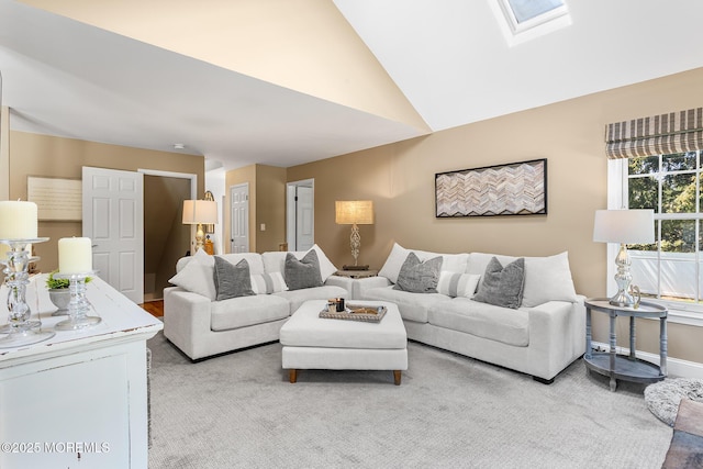 carpeted living room with baseboards and lofted ceiling with skylight