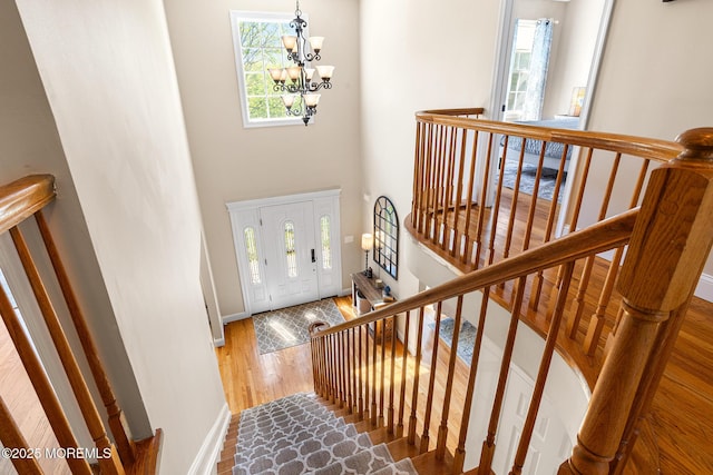 entrance foyer featuring baseboards, a high ceiling, wood finished floors, and a chandelier