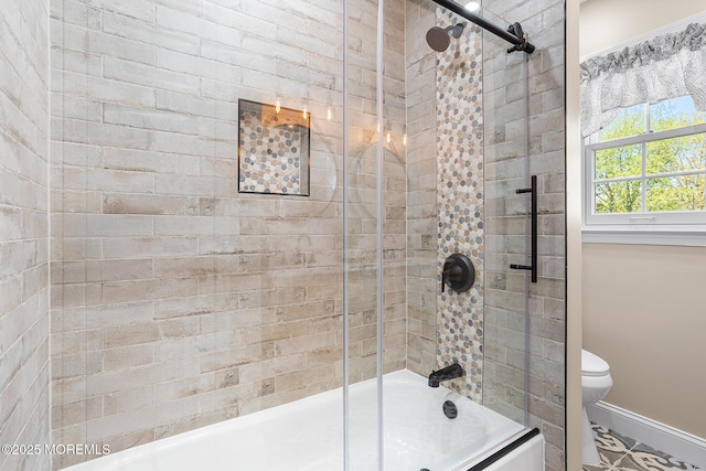 bathroom featuring toilet, baseboards, and combined bath / shower with glass door