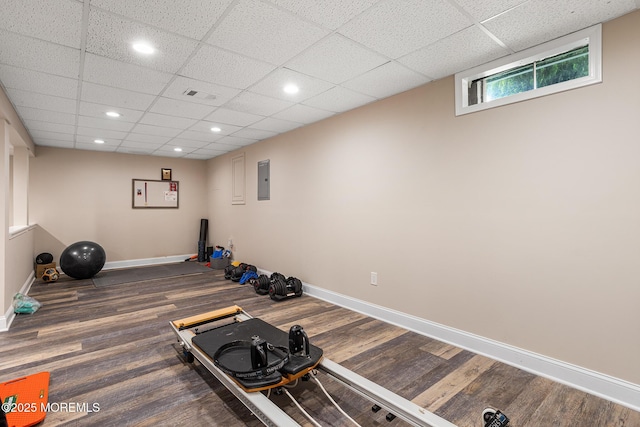 workout area featuring baseboards, recessed lighting, a drop ceiling, and wood finished floors