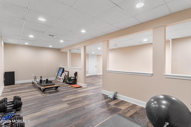 workout area with baseboards, visible vents, a drop ceiling, and wood finished floors